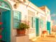 Bunte Djerba Hausfassade mit traditionellen blauen Fensterläden und Blumen in Tontöpfen, unter strahlend blauem Himmel, perfekte Kulisse für Auswandern nach Djerba.